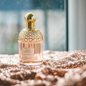 Elegant Guerlain perfume bottle on a textured fabric with natural lighting, exuding luxury and fragrance.